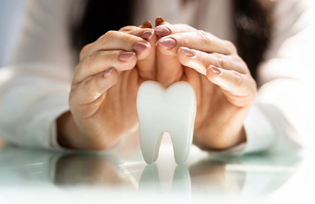 Hands breaking cigarette above tooth model, symbolizing dental health and smoking cessation benefits.