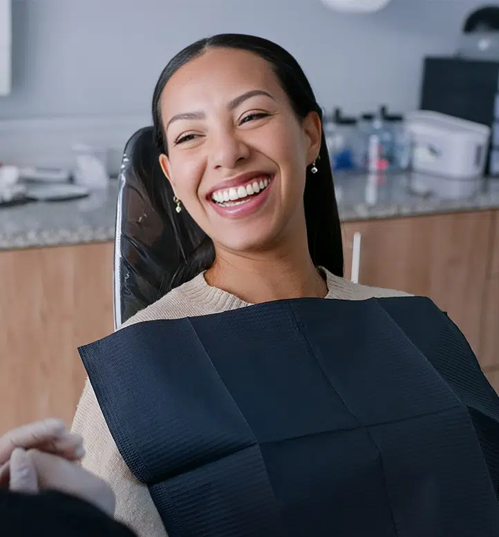 Female dentist smiling while holding patient chart in modern dental office