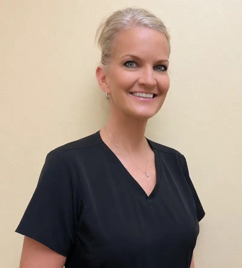 Professional woman in black scrubs smiling at dental office